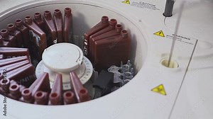 a lab worker doing a blood test. loads the tubes into the machine. The assistant loading the vial into the laboratory centrifuges. Changing blood vials.
