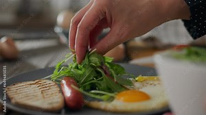 Kitchen. A woman cook in home clothes puts vegetables salad on a plate in the kitchen at home. Camera in motion, modern girl adds fresh salad vegetables to breakfast, sticks to healthy diet, toast