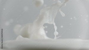 Fresh milk drop falling and splashing in a milky pool. Pouring milk in slow motion