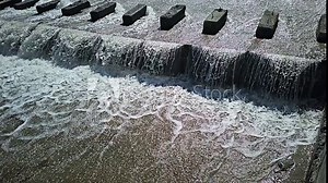 chute dentate blocks in concrete water spillway channel slope slowing down the flow of water running down super slow motion captured with a cellphone
