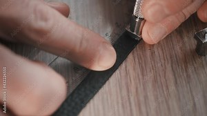 Up view and close up of leather craftsman who is punching letters on leather bracelet. Handmade accessories.
