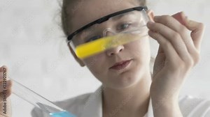 Teenage girl scientist comparing test tubes with colorful substance