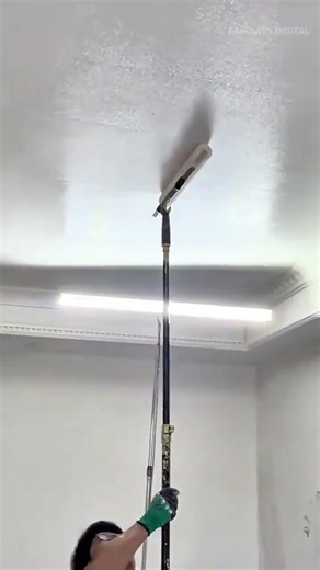 painting the ceiling with a long roller tool to ensure an even coating of white paint over