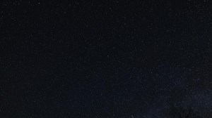 Time lapse of Starry night sky, A clear view of the night sky filled with countless stars, with the silhouette of a tree barely visible in the bottom right corner