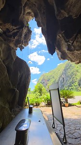 El bar más ESPECTACULAR de Cuba 🇨🇺 ¡Prepárate para alucinar! 🤯 Esto no es una cueva cualquiera, ¡es el Palenque de los Cimarrones en el Valle de Viñales, Cuba! De día es un bar increíble donde puedes tomarte un mojito rodeado de estalactitas con millones de años de historia. 🍹 Y de noche… ¡se transforma en una discoteca! 🕺💃 La sensación de estar de fiesta dentro de la tierra es algo de otro mundo, pero la verdadera magia es salir y encontrarte con esta vista espectacular. Es uno de esos lu