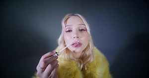 A woman in a yellow fur coat is smoking a cigarette