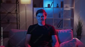 No way. Smiling man. Meme expression. Skeptic protesting guy shaking head expressing disagreement sitting sofa in dark neon light home interior looped.