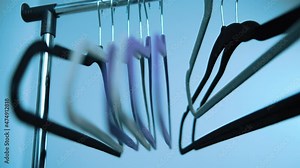 woman takes one of the multi-colored hangers in hand, hangers dangling close-up, choosing the right hanger