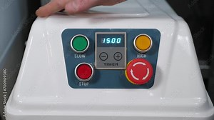 A close-up of the chef turns on a large industrial food processor for kneading burger dough in the restaurant kitchen, he presses the power button. A timer is turned on on the combine.