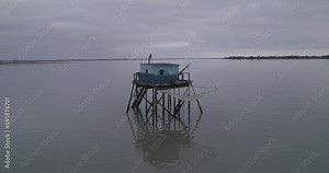 Bird's eye view of a building on columns in a sea against an island in France on a cloudy day