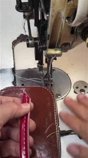 sewing the shiny brown leather material precisely using a professional electric machine tool today