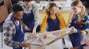 Overhead shot of multi-cultural team in workshop assembling hand built sustainable bamboo bicycle frame