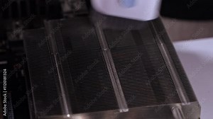 Cleaning CPU cooler heat sink using a specialized brush to remove dust and improve cooling efficiency for optimal PC performance
