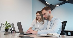clip-1069898194-two-creative-businessmen-sitting-desk-they-solving