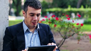 Man at a park using a computer tablet computer looking at camera