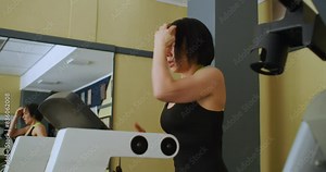 Caucasian woman in excellent physical shape while working out on a treadmill. Cardio exercise on a treadmill. Physical education as a norm of life for maintaining health. Slow motion in 4k format.