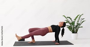 Yoga brunette woman performs a variation of the Purvottanasana exercise, inverted table pose with straight leg lifting up, strengthens the muscles of the legs and abdomen, trains in the room on a mat