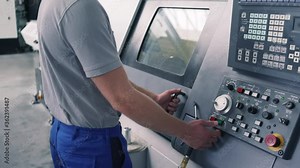 Competent worker operating CNC lathe machine on factory floor
