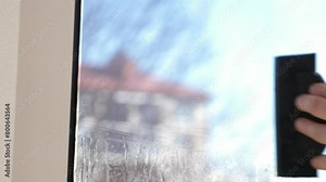 Worker installing and smoothing tint film on window at home. Man tinting windows with squeegee