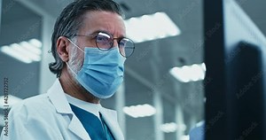 Middle aged doctor using computer in laboratory
