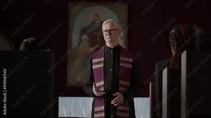 Senior catholic priest talking to three people during funeral ceremony in church