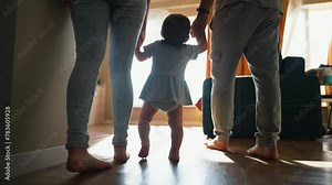 First steps. Family day. toddler takes first steps at home across field. parents hold hands of baby learn to walk. Happy baby takes first steps on floor of house.toddler dream to learn the first steps