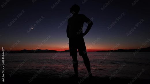 Man on the beach with young crescent Moon with stars and planets over ocean sea waters.