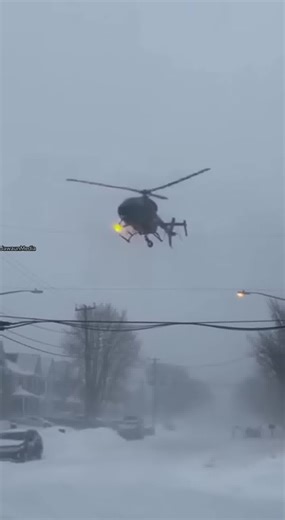 News Helicopter Crashes on Residential Street During Blizzard 🚁❄️ Buffalo, New York — Tuesday, February 25, 2025 Smartphone footage shows a news helicopter flying low over a wide residential street during a heavy blizzard when its rotors clip an overhead power line. Sparks shower down onto the snow-covered road as the helicopter spins out of control and crashes hard, sliding across the street before striking a fire hydrant. Emergency crews responded quickly to secure the aircraft and downed pow