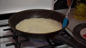 Europe, Kiev, Ukraine - March 2020: a girl bakes pancakes in a pan. Pan with pancake on a gas stove.