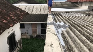 The feet of an Asian Indonesian man are walking barefoot on the edge of asbestos cement to check for leaks