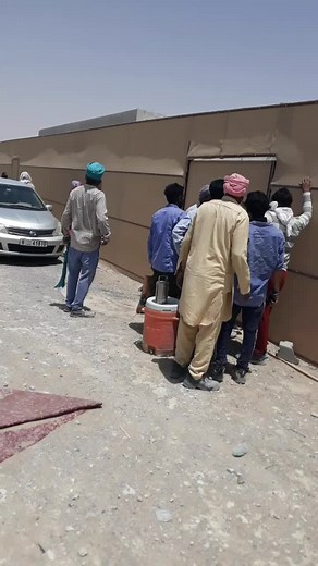 Group of Men Painting a Wall Outdoors Together