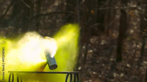 Yellow spray paint can being shot in slow motion by which it explodes and splatters aerosol paint everywhere under high pressure and begins to fly around because of it. Background is blurred slightly. Stock Video