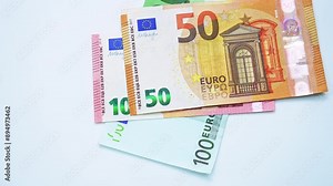 Falling euros banknotes and pile of euro currency banknotes are spinning on table