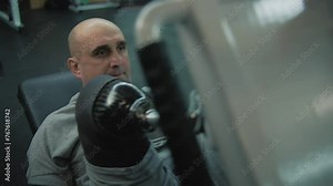 Motivated athlete with prosthesis on leg trains on leg press machine in modern fitness center. Adult sporty man with physical disability does strength training using professional sports gym equipment.