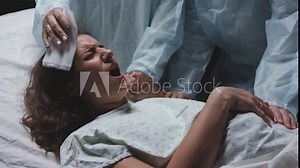 young mother screams and cries during childbirth, maternity hospital, strong pain, caucasian woman contractions, obstetricians gynecologists and midwives support Stock Video