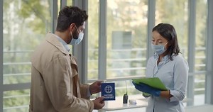 Businessman in mask enter commercial building and show vaccination passport at entrance. Female security in safety mask with clipboard check vaccination certificate of visitors