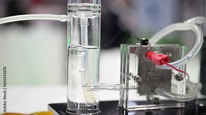 Hydrogen bubbles forming in a plastic cylinder filled with water, a fuel cell demonstrator splits water into oxygen and hydrogen, slow motion