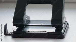 office work, a man uses a hole punch to make holes in the paper.
