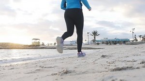 Young athletic woman running along the beach
