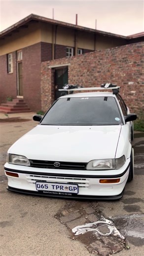 Modified White Car with Custom Wheels and Roof Rack