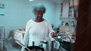Elderly Senior African American woman preparing meal at home in casual domestic lifestyle scene in South America, one gray hair older black lady cooking
