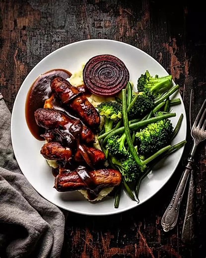 Perfectly cooked, juicy sausages, nestled on a bed of silky, buttery mashed potatoes. Served with tender steamed broccoli and crisp fine green beans, and topped with sweet caramelised red onions and a rich, glossy onion gravy. Comfort food done right—hearty, satisfying, and impossible to resist. #sausages #food #mashedpotatoes #caramelisedonions #oniongravy
