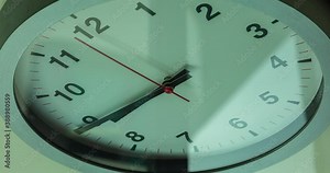 Wall clock show the running time. Time lapse on a modern wall clock. Close up to a wall clock, with running time pointer. Sun and sky reflecting in the watch during the time passing by