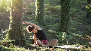 Woman is practicing yoga in nature. Seated gentle easy pose for relief.