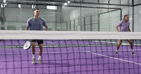 clip-4048065655-diverse-male-pair-lunging-volleying-yellow-ball