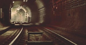 CGI Mysterious underground railway tunnel with tracks and dim lighting