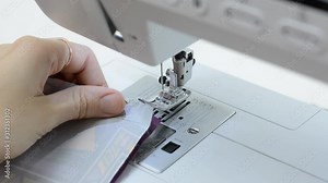 A seamstress sews clothes using a sewing machine. Needle and thread penetrate through the fabric, the movement of the needle. The stitching of the thread.
