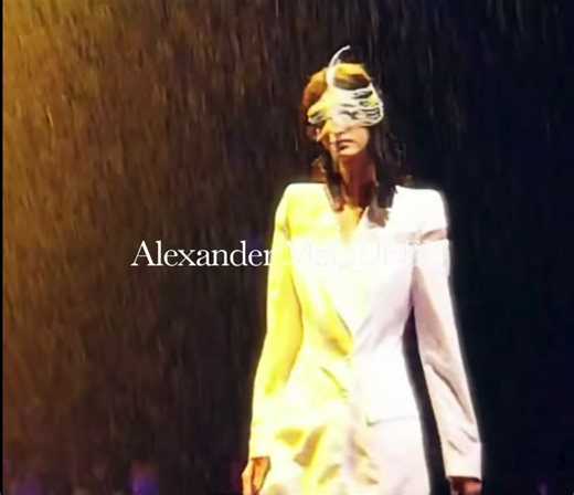 In 1998, Alexander McQueen - already known for pushing fashion into visceral performance - staged one of the most unforgettable shows in runway history. Originally titled The Golden Shower but renamed Untitled after sponsor pushback, the Spring/Summer '98 presentation transformed a derelict London bus depot into a dramatic stage. Models walked above water-filled tanks under flashing lights while thunder and rain suddenly poured from above, drenching garments and makeup alike, turning pristine fa