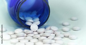 White tablets with little red points and blue jar for nutritional supplements on the table. Overdose theme. In reality these are chromium picolinate tablets. Cinema 4K 60fps video with cinema effects