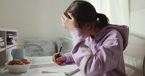Exhausted or sick upset school student studying alone feeling headache writing difficult assignment at home. Tired depressed bored teenage girl worried about problem in children education concept.